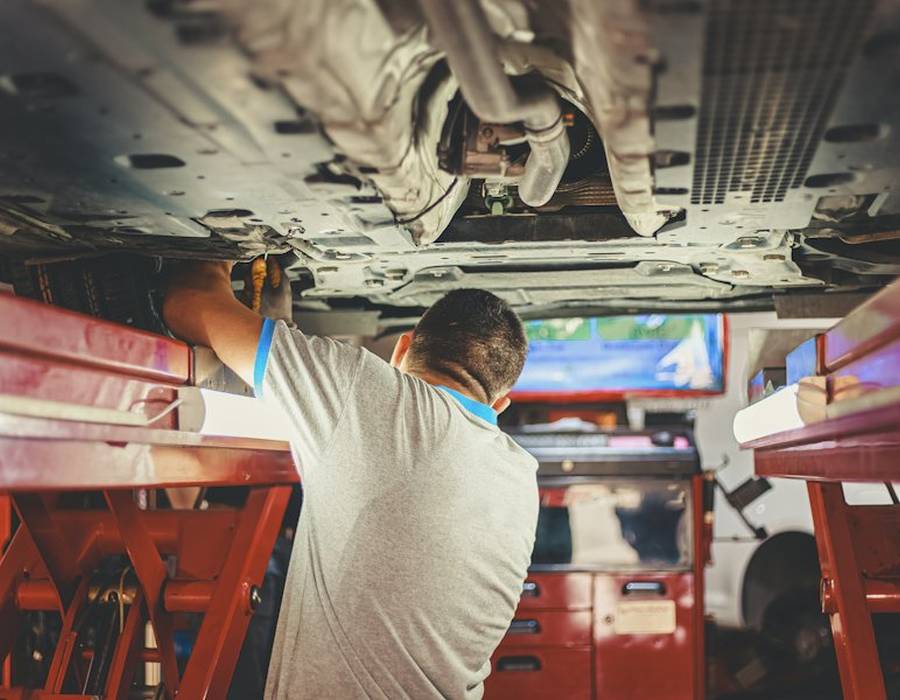 Inside the shop: a technician working under a lifted car